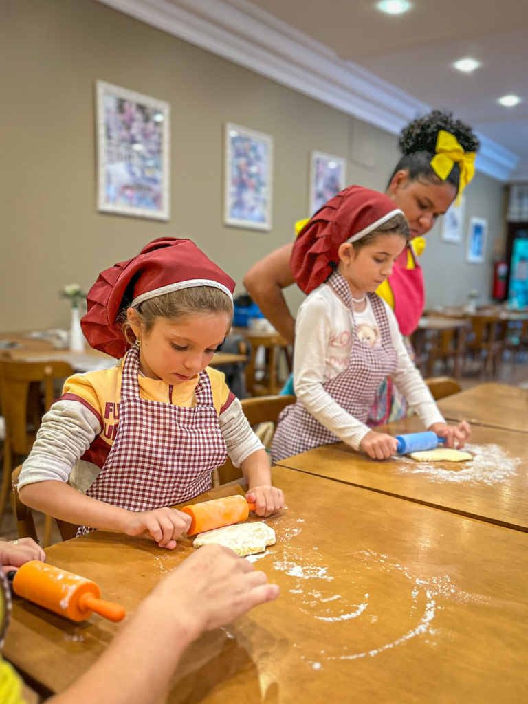 Duas meninas se divertindo enquanto cozinham durante o momento de recreação no Hotel Recanto da Serra no carnaval em Gramado.