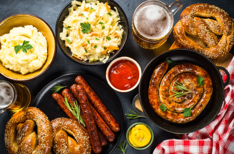 Mesa com pratos típicos da culinária alemã como salsichas pretzels chucrute purê de batata e cerveja representando a experiência gastronômica em um restaurante alemão em Gramado